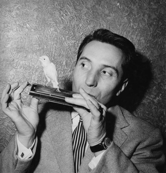 Albert Raisner playing the chromatic harmonica, with a canary perched on the instrument