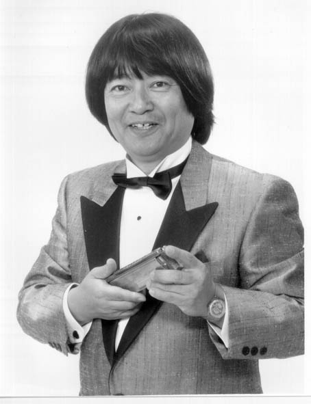 Juko Saito, creator of the pentatonic tremolo harmonica, holding a harmonica